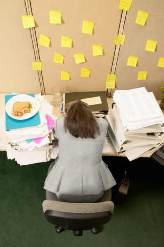 78747047_Overwhelmed_Woman_with_Head_Resting_on_Her_Desk