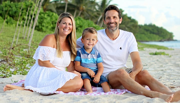 a smiling family with a mother father daughter and son at the beach sitting on a blanket-1