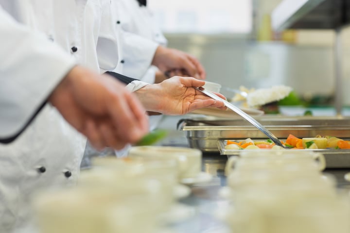 Chefs standing in a row preparing food in a modern kitchen