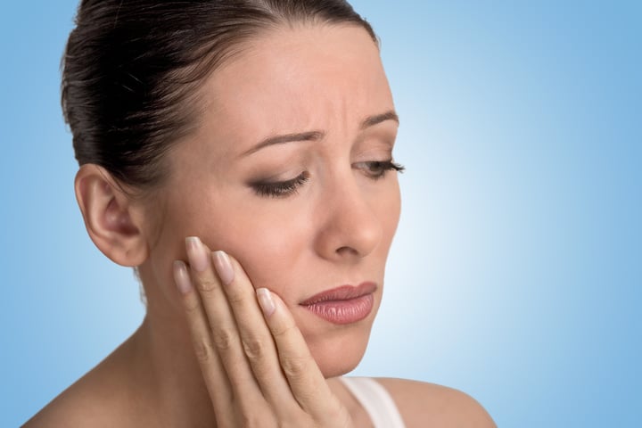 Closeup portrait young woman with sensitive tooth ache crown problem about to cry from pain touching outside mouth with hand isolated blue background. Negative emotion facial expression feeling-2