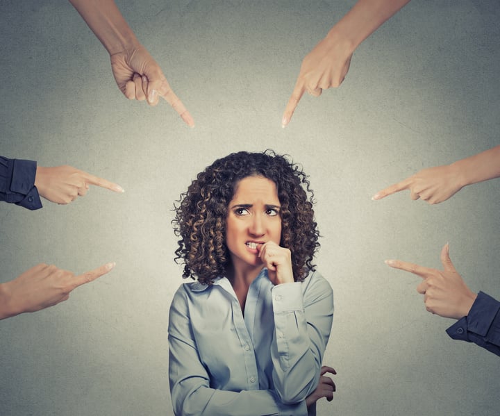 Concept of social accusation of guilty businesswoman many fingers pointing at isolated on grey office wall background. Portrait scared anxious embarrassed woman biting fingernails