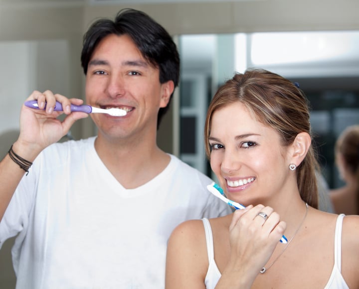 Couple with a toothbrush brushing their teeth and smiling
