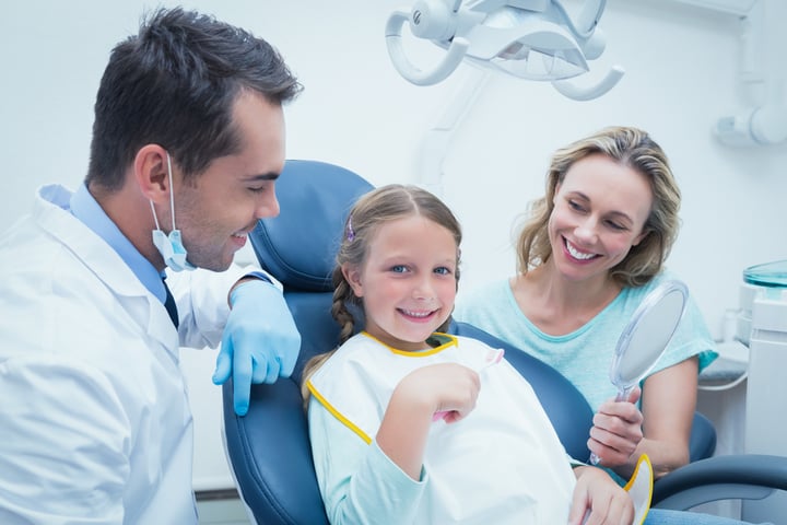 Dentist examining girls teeth in the dentists chair with assistant-2