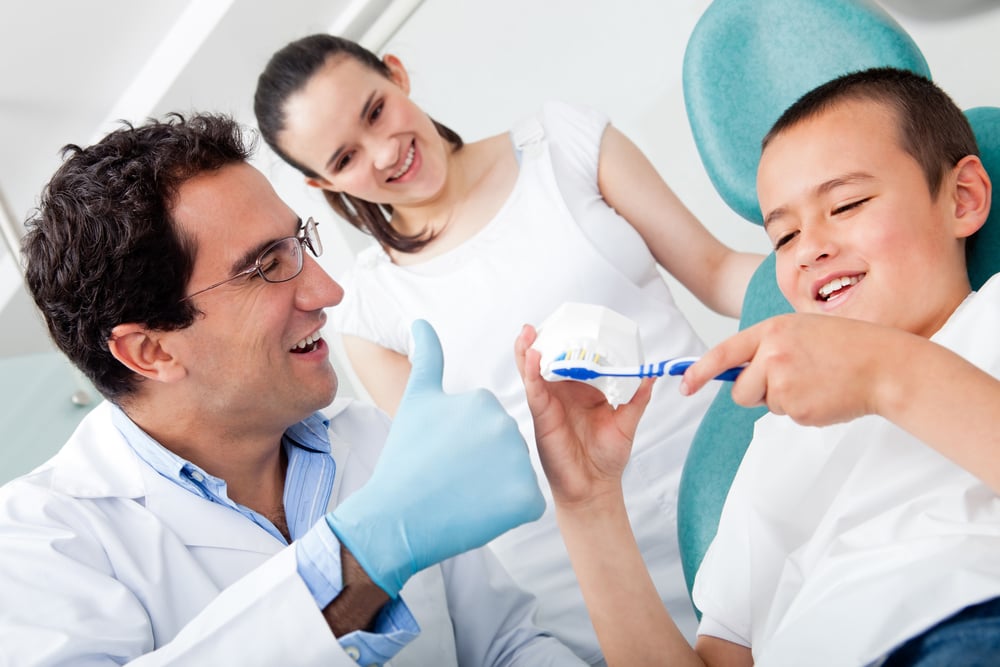 Dentist showing a boy how to brush his teeth properly