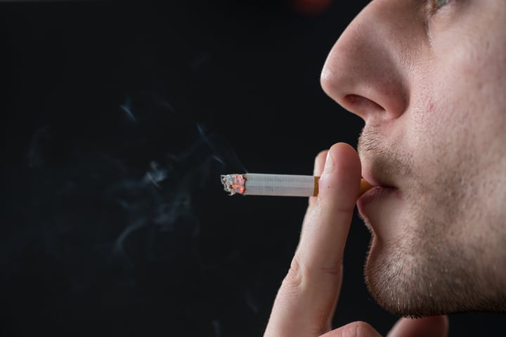 Man smoking cigarette on black background