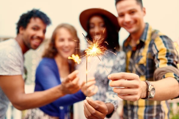 Multi-ethnic millenial group of friendsfolding sparklers on rooftop terrasse at sunset