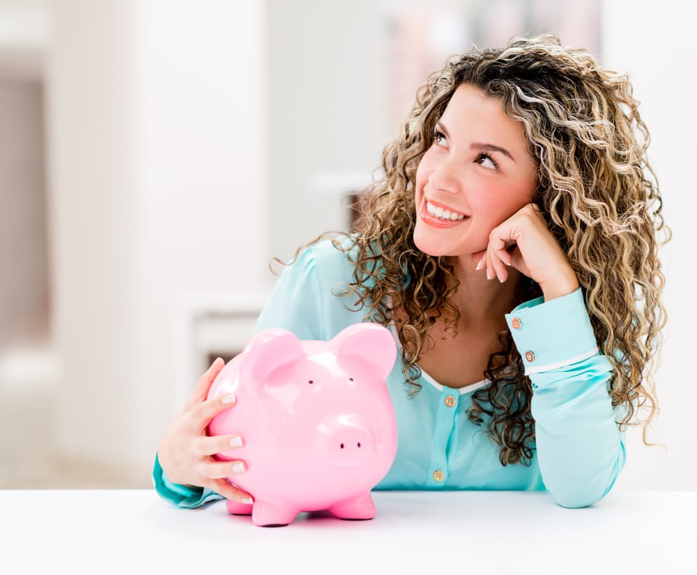 Thoughtful woman with a piggybank looking very happy