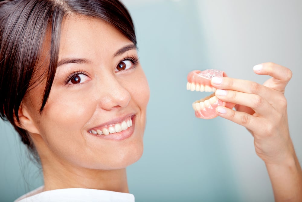 Woman holding a teeth sample or prosthesis at the dentist-1