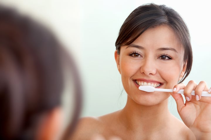 Woman in front of a mirror brushing her teeth-1