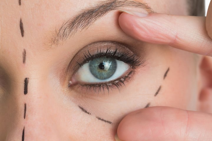 Woman opening the green eye with her hand in the white background