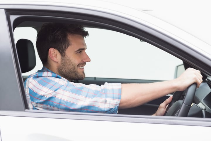 Young man driving and smiling in his car