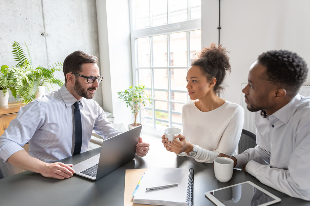 A smiling insurance broker meeting with a couple