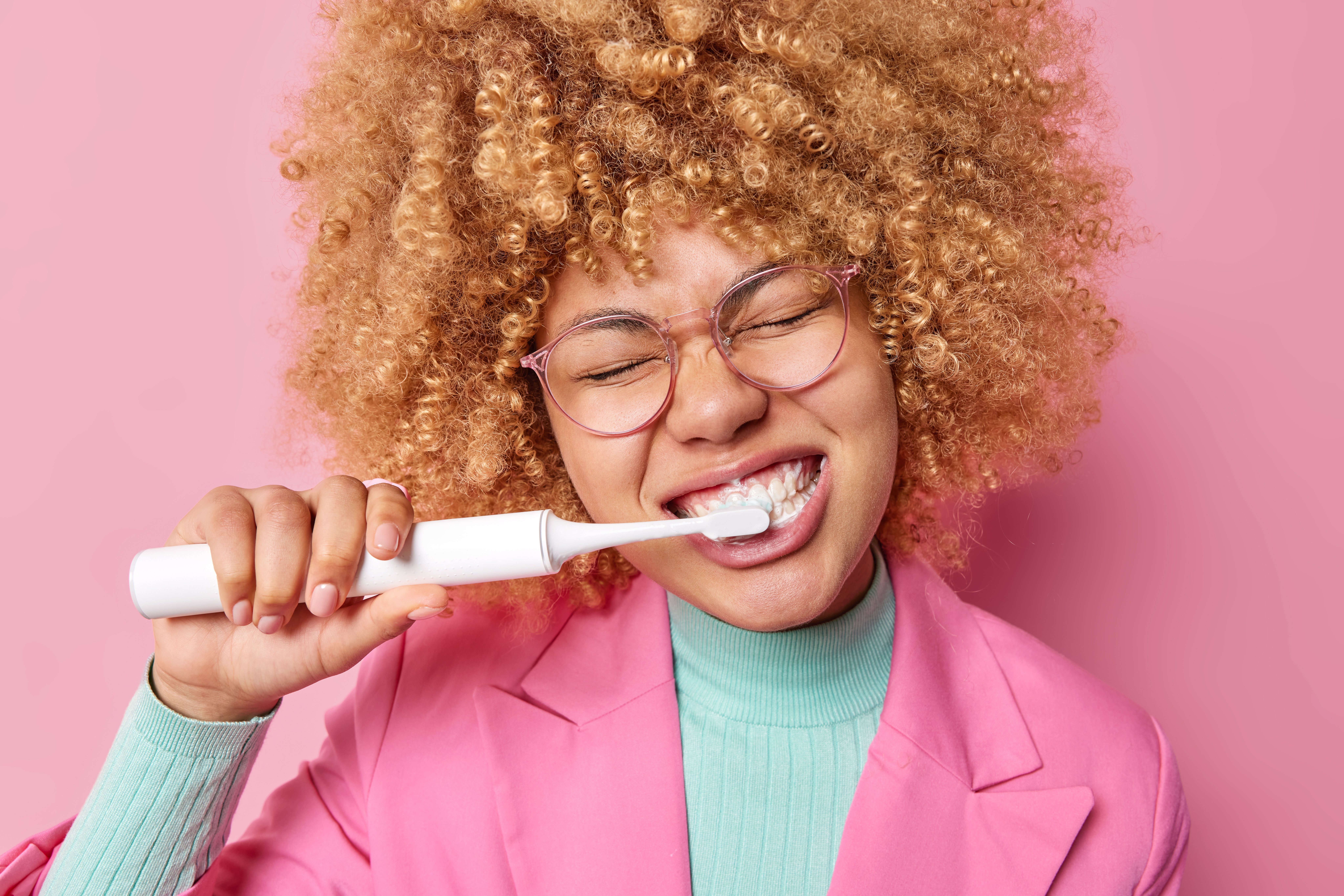 Woman brushing her teeth in a pink jacket