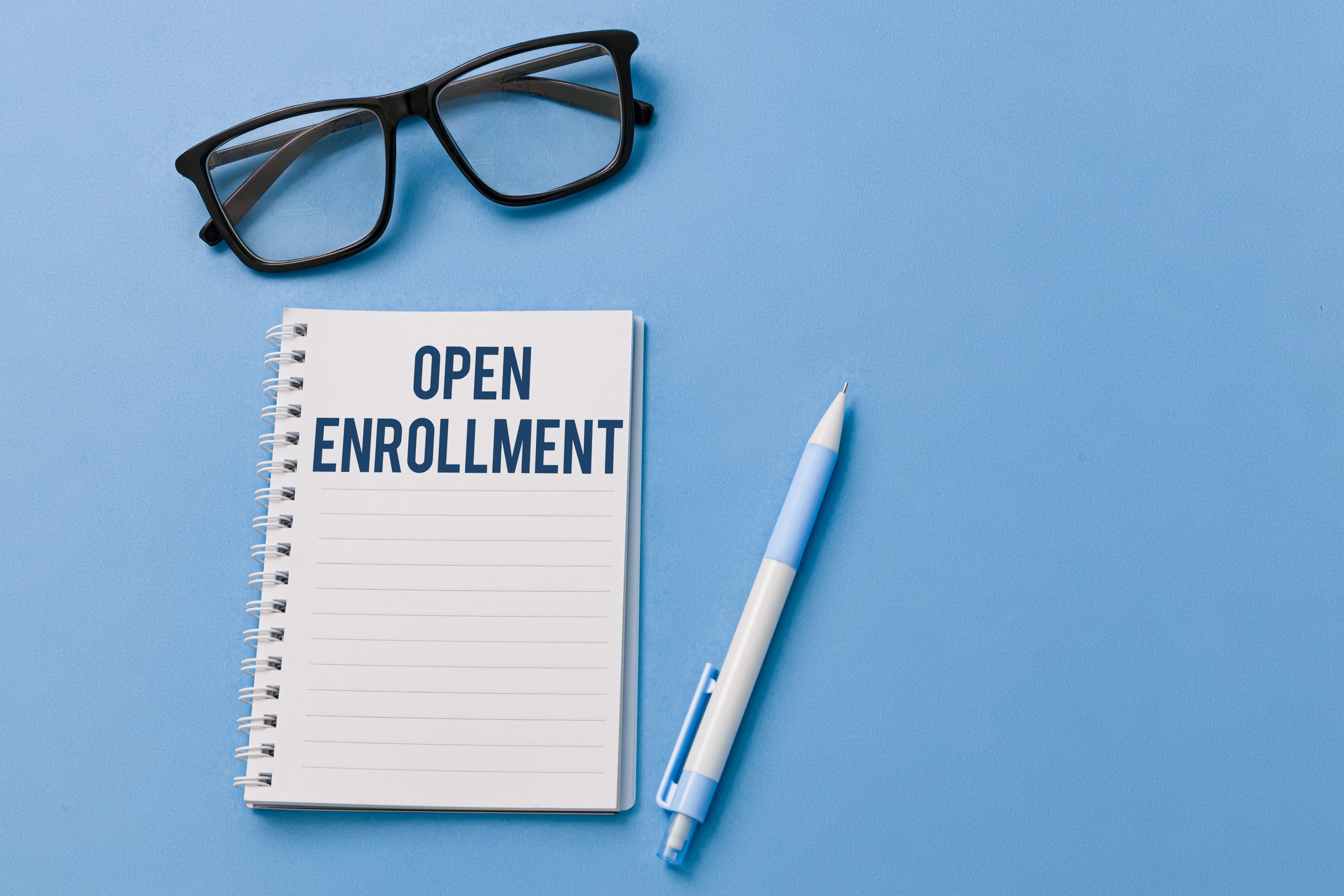 Glasses, a notepad and a pen on a desk for open enrollment