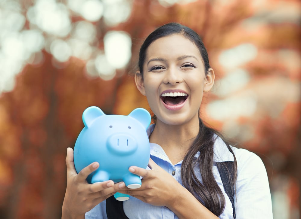 Smiling woman holding a piggy bank outside
