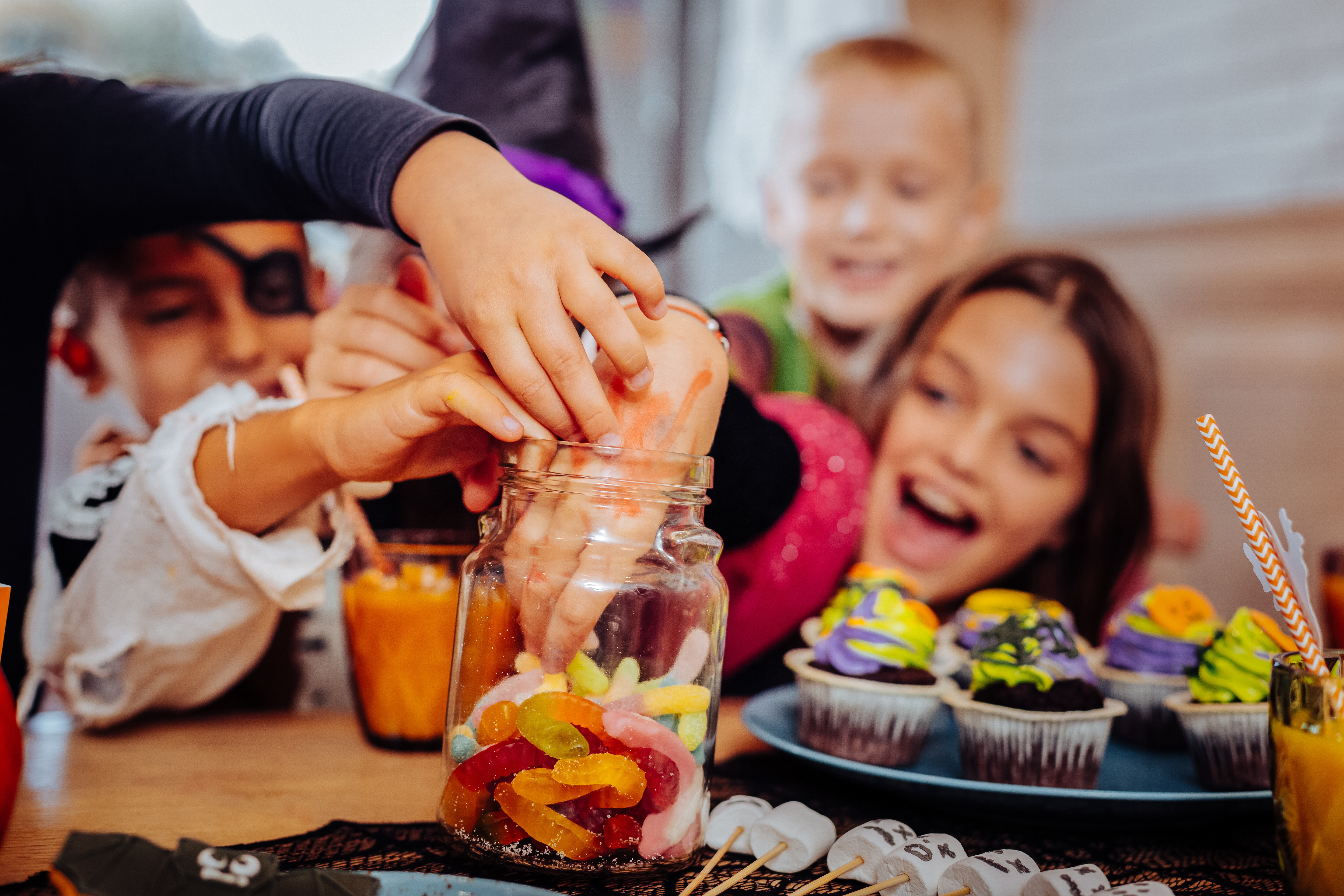 A group of children wearing Halloween costumes and reaching into a bowl of candy