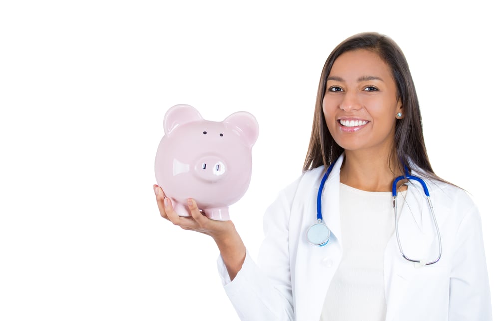 A female medical provider smiling and holding a piggy bank