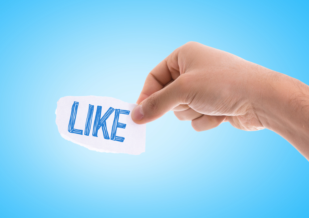 A hand holding a social media like button 