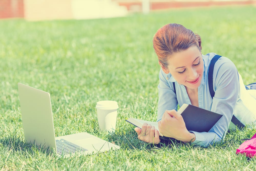 Image of a professional woman learning with a book and  laptop
