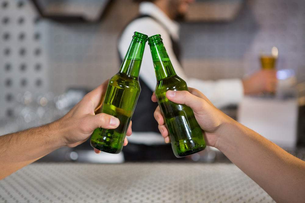 Two people clinking beer bottles