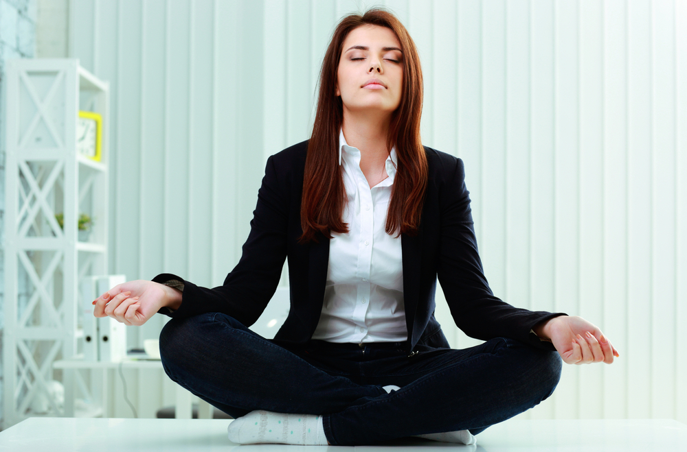 A businesswoman meditating in her home office.