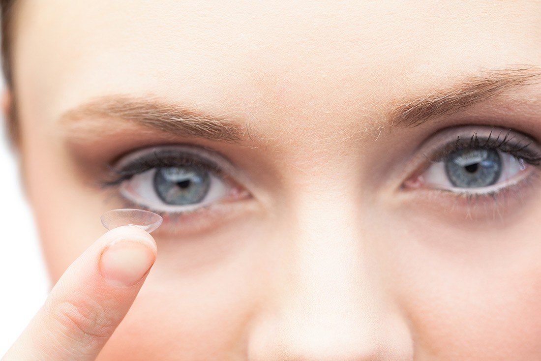 Woman holding up a contact lens